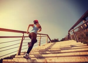 woman in black workout leggings running up stairs outdoors
