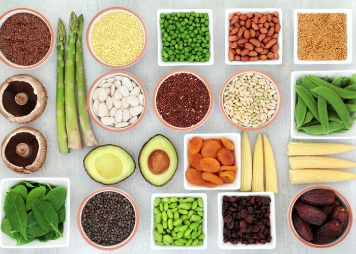 Top down view of flexitarian-friendly foods such as vegetables, seeds and nuts laid out neatly in small bowls on a grey table