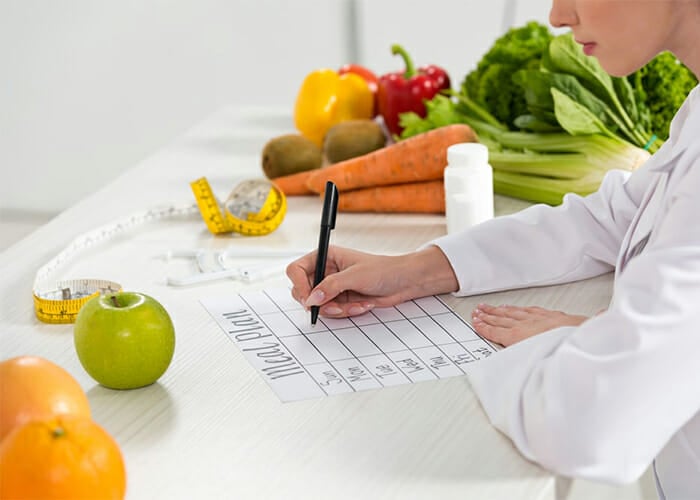 Woman writing out a Paleo diet meal plan on a piece of paper