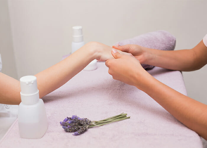 A woman getting a hand massage with lavender essential oil by a masseuse 