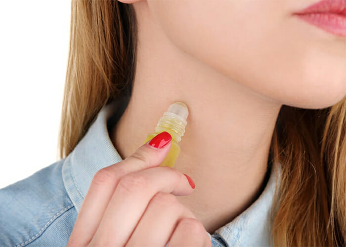 Woman using homemade essential oil perfume on her neck