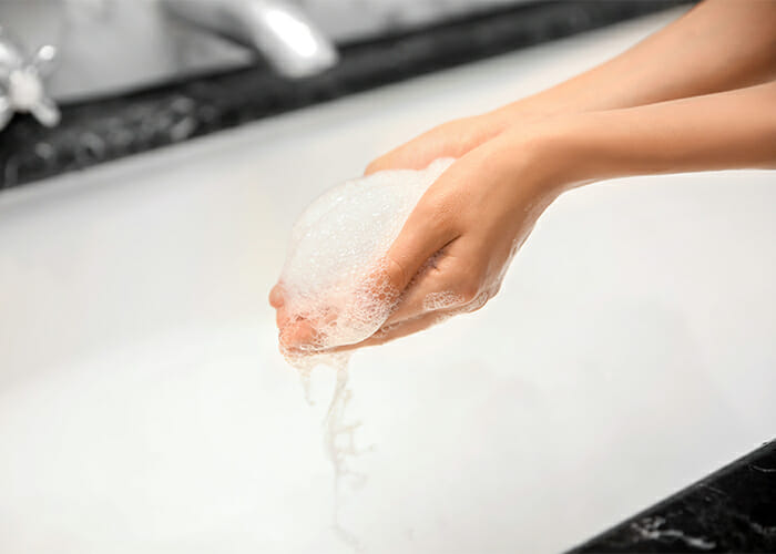 Woman holding foam from a bubble bath made from bergamot essential oil