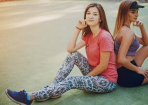 two women sitting outdoors in stylish workout gear for women