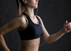 woman jogging in a black sports bra and listening to music