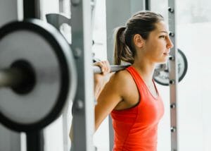 woman in orange fitness top doing weights at the gym