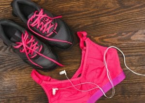 flatlay of a pink sports bra and black sneakers with pink laces