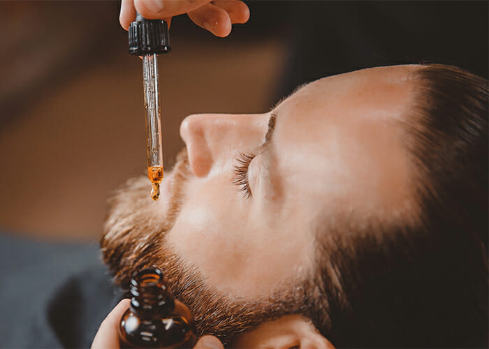 Barber applying a DIY Essential Oil Blends For Beard Oil in Beary Hairy scent