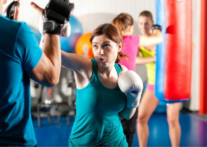 Woman in a kickboxing class practicing with boxing pads
