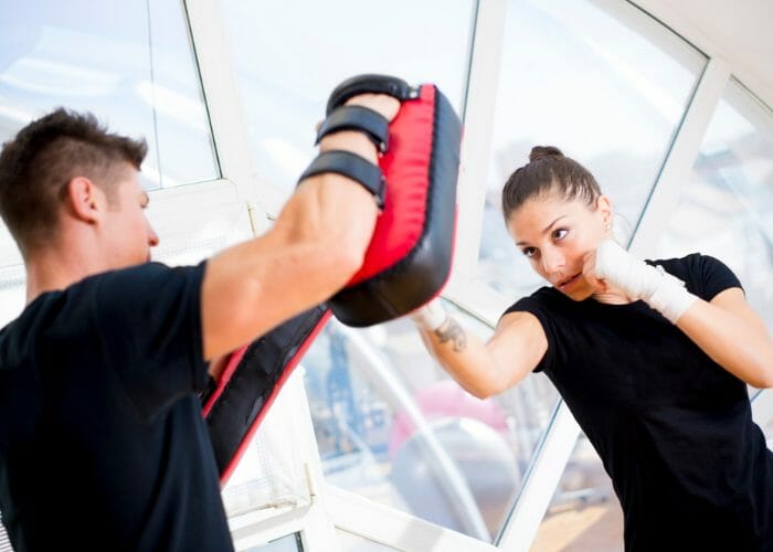 Young fit female doing kickboxing exercises with an instructor