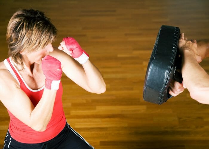 Top down view of fit woman with short hair practicing kickboxing with an instructor