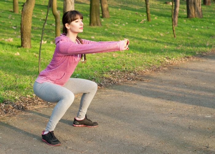 woman doing simple squats in a park