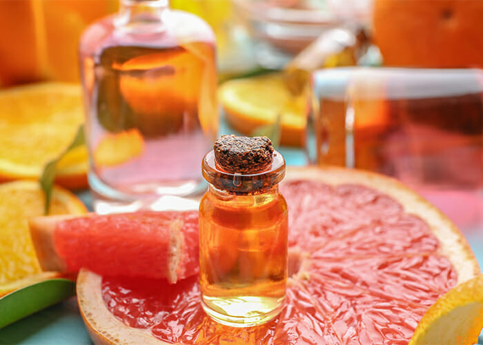 A bottle of grapefruit essential oil on top of a slice of grapefruit