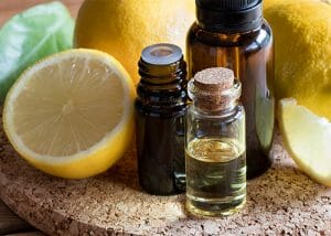 Different sized bottles of lemon essential oil on a cork plate