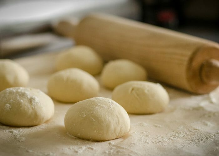balls of cassava flour pizza dough with a rolling pin in the background