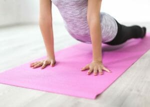 woman performing downward dog yoga pose on a pink yoga mat