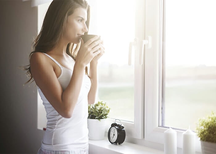 Woman at her window drinking a Keto-approved drink in a mug