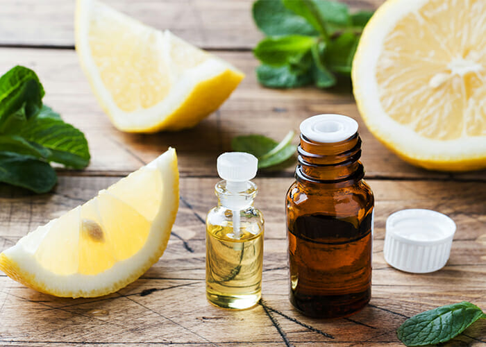 essential-lemon-oil-in-bottle-with-fresh-fruit-slices-on-wood