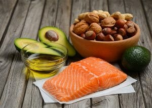 A variety of healthy keto diet fat sources including nuts, avocado, salmon, and olive oil