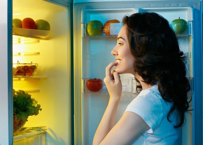 Woman trying to find a late night snack in her fridge