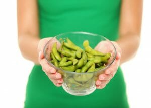 A woman holding a bowl of freshly cooked edamame ready to eat as a healthy late night snack