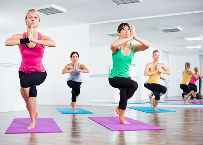 A group of women holding an advanced hot yoga pose in class