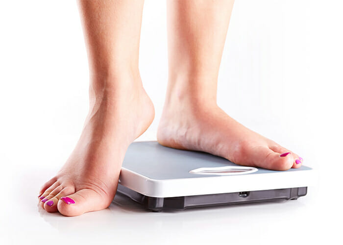 A woman weighing herself on the scale