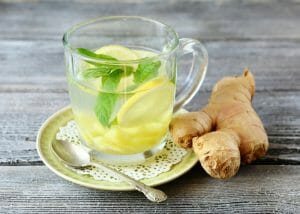 glass of lemon and ginger tea with a sprig of mint leaf