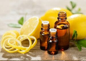 Lemon essential oil bottles next to lemon rind and whole lemons