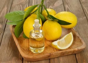 A wooden tray with a bottle of homemade lemon essential oil and a bunch of lemons still on the stem
