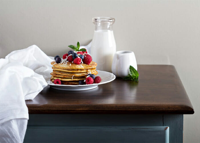 A stack of freshly made Paleo coconut flour pancakes topped with fresh berries on a plate 