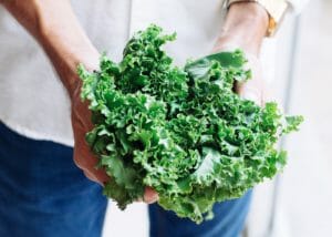 Woman holding onto a bunch of green leafy vegetables