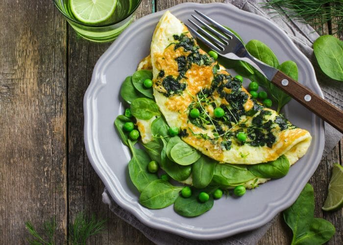 a superfood omelet of eggs, spinach and green peas on a purple plate