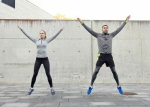 woman and man doing jumping jacks outdoors