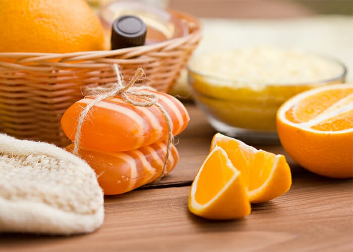 Handmade citrus essential oil soaps next to freshly cut oranges