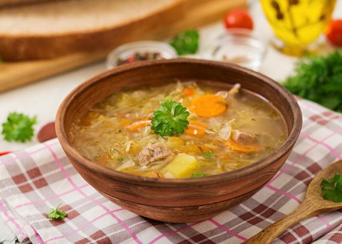 Homemade vegan and carrot sauerkraut soup in a brown ceramic bowl
