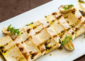 vegan grilled tofu dressed in oil on a white plate