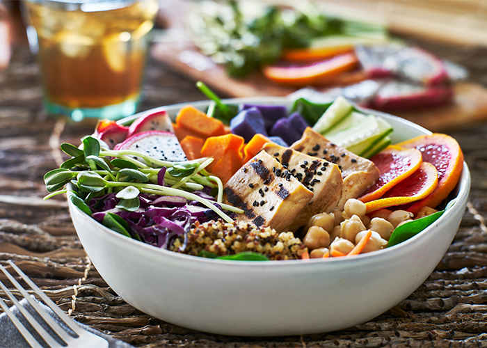 Colorful vegan Buddha bowl with tofu, dragonfruit, sprouts, chickpeas, greens, and pumpkin.