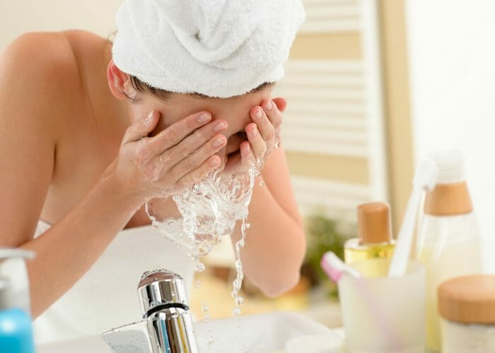 woman in the bathroom splashing her face with water