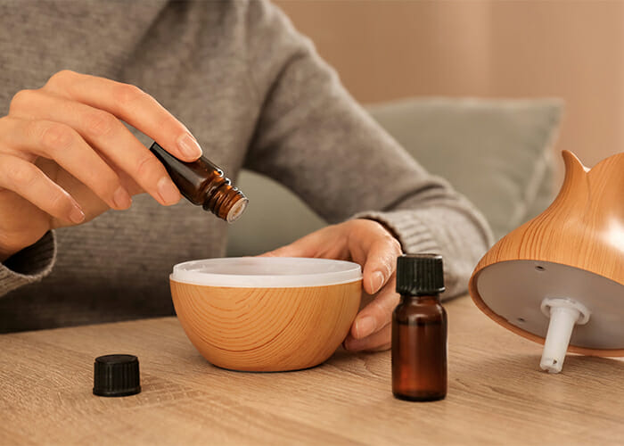 Woman putting an essential oil blend into a wooden essential oil diffuser.