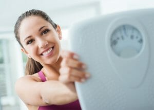 Woman happy with keto weight loss results holding up a scale