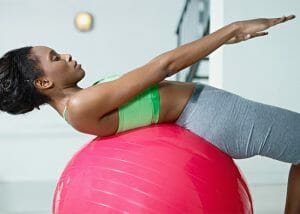 Woman working out on a balance ball to get over keto weight loss plateau