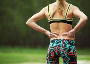 The back of a woman in fitness gear with her hands on her waist