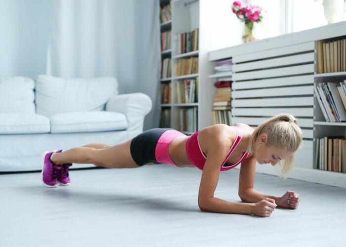Young woman doing low plank bodyweight back exercises