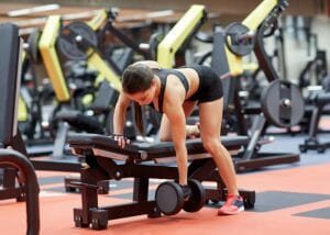 Woman doing dumbbell exercises on a bench at the gym