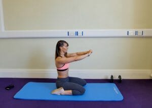 woman kneeling on an exercise mat doing butt exercises