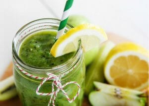 green smoothie in a jar with a straw and slice of lemon