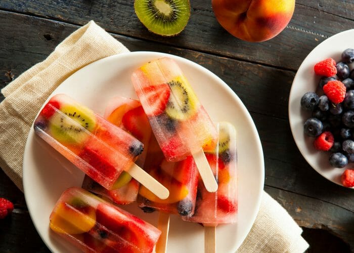 frozen fruit popsicles piled on a white plate