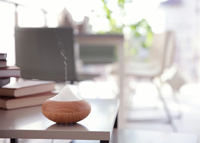 A diffuser on a table with summer essential oil diffuser blends